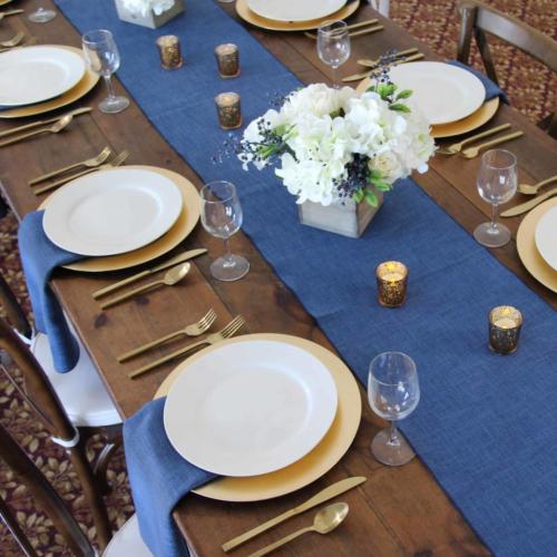 White china, gold chargers, gold silverware & blue panama linens