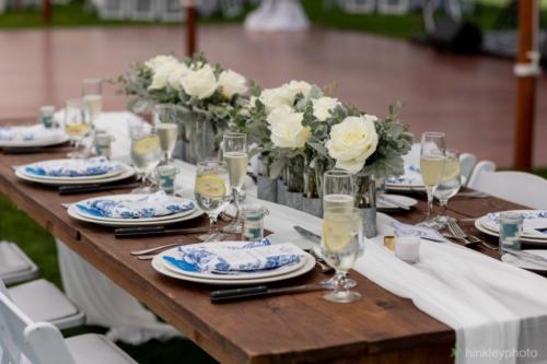 Farm tables with white linen runners and white garden chairs